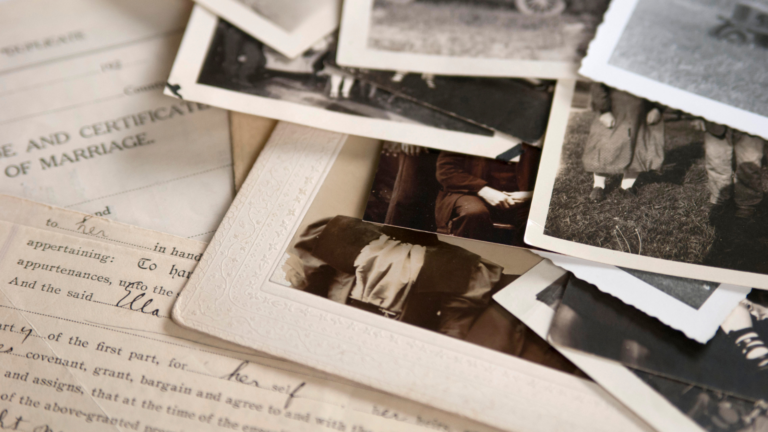 Collection of old photographs on top of historical documents scattered about.