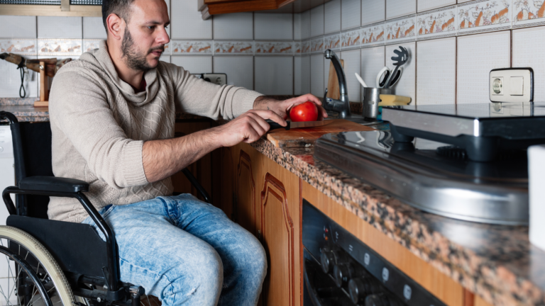 Man in wheelchair cuts an apple on the counter.